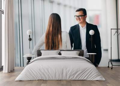 Businessman and Businesswoman shaking hands in office with big panoramic windows in office hall Wall mural